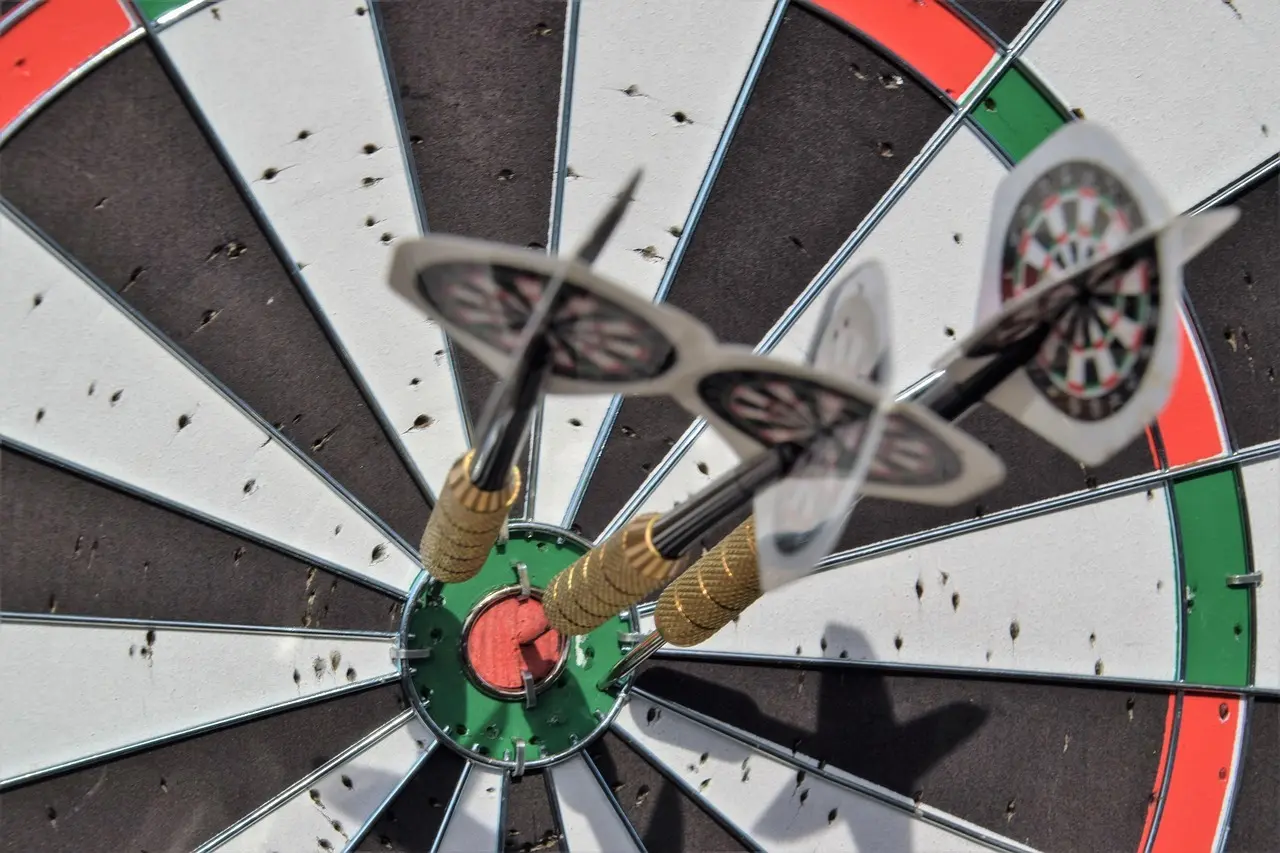 Tre dartpile i bullseye på et dartbræt